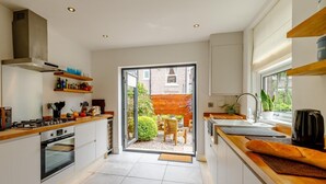 Une cuisine moderne dotée d’un îlot central, d’un four encastré et d’une porte-fenêtre coulissante donnant sur un patio.