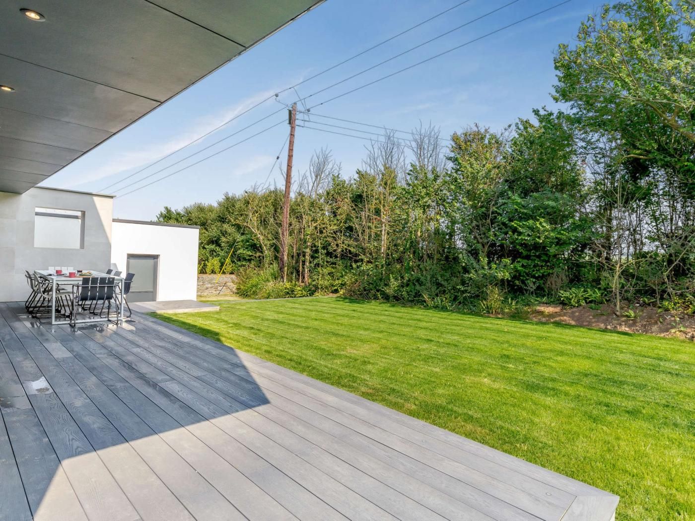 Une terrasse extérieure moderne, dotée d’une plateforme en bois, d’une table à manger et de chaises.