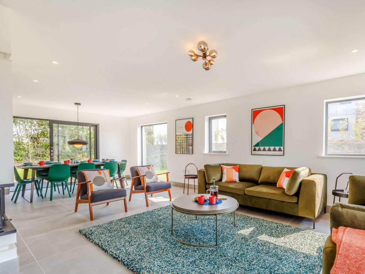 Un salon moderne avec un canapé, une table basse et des fauteuils, un coin repas avec une table et des chaises, et des œuvres d’art accrochées aux murs.