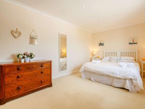 Ein Schlafzimmer mit Bett, Kommode, Spiegel und Wandbildern.