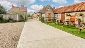 A rural street with stone houses, a gravel path, and picnic tables. - 3 Bed in Pickering (oc-88956) (Newton-on-Rawcliffe)
