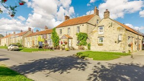 A row of stone buildings with a paved street, outdoor seating, and greenery. - 3 Bed in Pickering (oc-88956) (Newton-on-Rawcliffe)