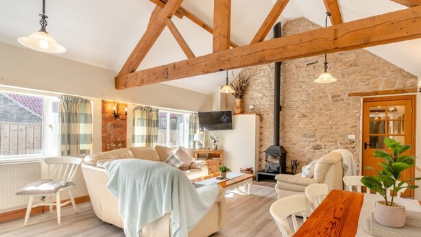 A cozy living room with a sofa, chairs, a wooden table, a stone wall, and a fireplace. - 3 Bed in Pickering (oc-88956) (Newton-on-Rawcliffe)