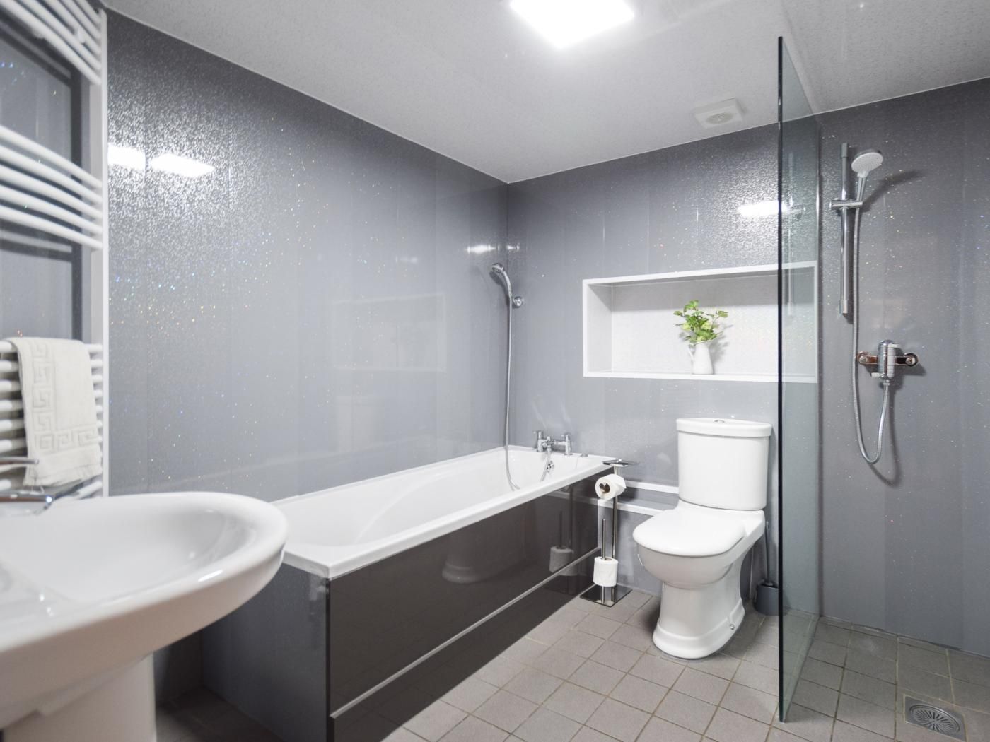 A modern bathroom with a bathtub, toilet, and shower.