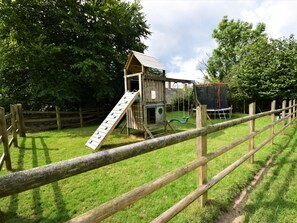 A wooden play structure with a slide and a swing set, surrounded by a wooden fence. - 2 Bed in South Molton (oc-88992) (Bishops Nympton)