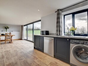 A modern kitchen with a large window, a dishwasher, and a washing machine. - 2 Bed in South Molton (oc-88991) (Bishops Nympton)
