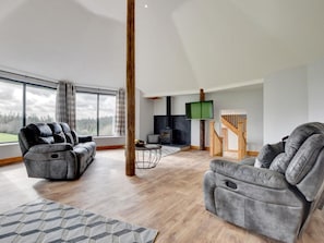 A spacious living area with two grey sofas, a wooden floor, a fireplace, a TV, and a staircase. - 2 Bed in South Molton (oc-88991) (Bishops Nympton)