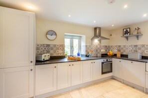 A kitchen with white cabinets, a built-in oven, a toaster, and a window. - 2 Bed in Abergele (oc-88974) (Llanfair Talhaiarn)