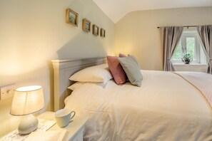 A neatly made bed with pillows, a bedside lamp, and a cup on a nightstand. - 2 Bed in Abergele (oc-88974) (Llanfair Talhaiarn)