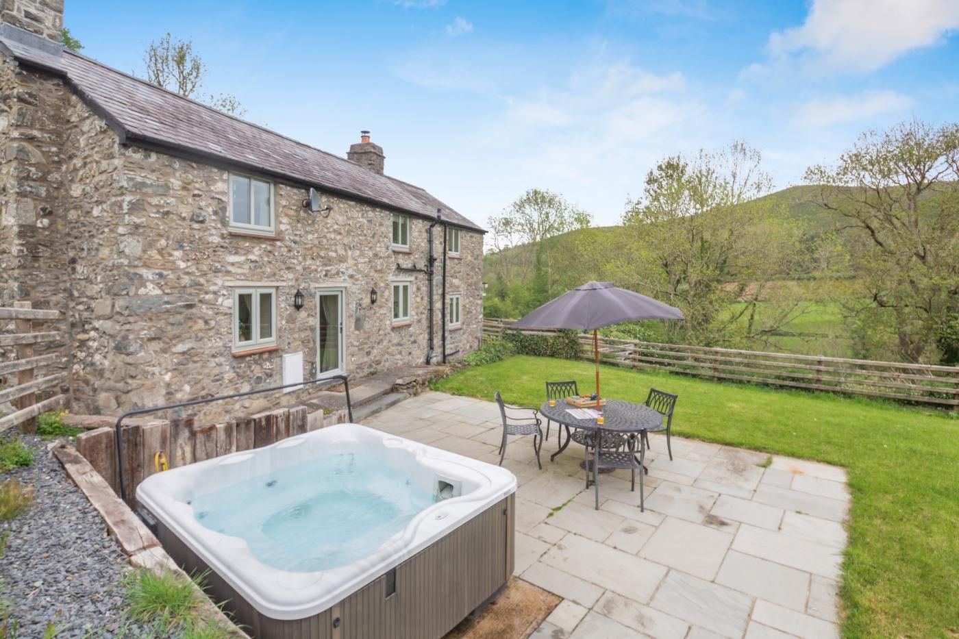 A stone building with a hot tub and outdoor seating.