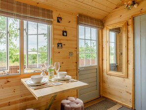 A wooden cabin interior with a dining table set for two, a bottle of wine, and a bowl. - 1 Bed in Darlington (oc-88970) (Stapleton)