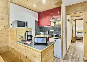 A kitchen with wooden cabinets, a microwave, a toaster, and a red backsplash. - 200m from ski slopes, 5th floor, view ski slopes, balcony, tv, 33m², Tignes (Tignes)