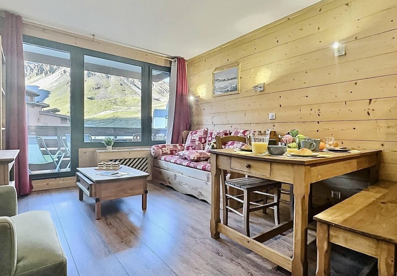 Una habitación acogedora con una pared de madera, un sofá, una mesa de comedor y vistas a las montañas a través de amplios ventanales.