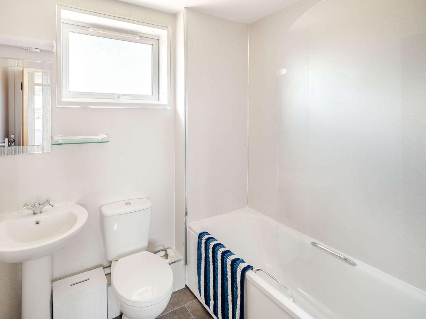 Et badeværelse med toilet, vask og badekar.