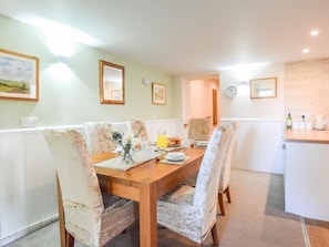 A dining area with a wooden table and chairs, a small kitchen area with a sink and countertop, and framed artwork on the walls. - 3 Bed in Pickering (oc-88958) (Newton-on-Rawcliffe)