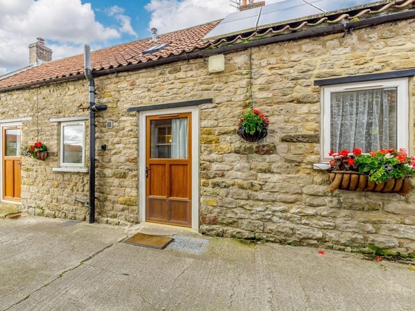 A stone building with a tiled roof, a wooden door, and windows with curtains. - 3 Bed in Pickering (oc-88958) (Newton-on-Rawcliffe)