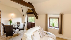 A room with a bed, a dining table with chairs, a window with curtains, and a stone wall. - 2 Bed in Pickering (oc-88957) (Newton-on-Rawcliffe)