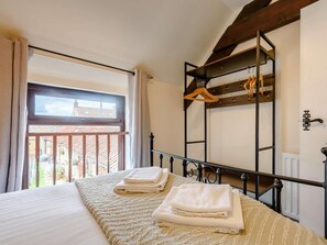 Et soveværelse med seng, et vindue, en balkon og et metalstående skab.