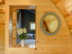 A wooden interior with a window, a mirror, and a vase with flowers.