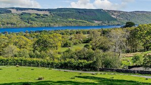 A scenic landscape with a lake, rolling hills, and a stone wall.