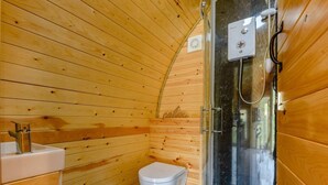 A wooden-paneled bathroom with a toilet, sink, and glass-enclosed shower.