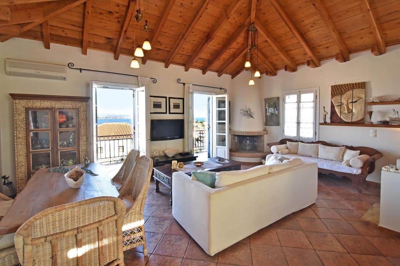 Uma sala de estar espaçosa com teto de madeira, televisão, lareira e vista para o exterior.