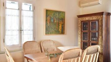 Un comedor con sillas de mimbre, una mesa de madera y un armario con puertas de cristal.