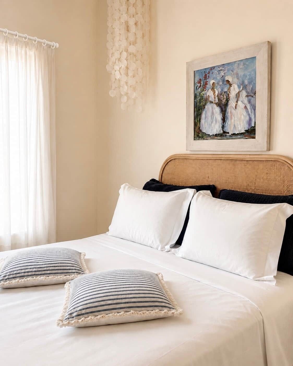 Une chambre à coucher avec un lit, des oreillers, une tête de lit et un tableau accroché au mur.