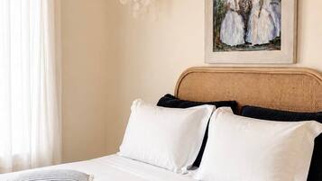 Une chambre à coucher avec un lit, des oreillers, une tête de lit et un tableau accroché au mur.