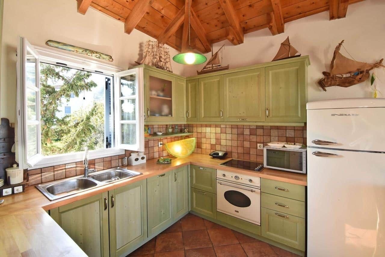 Une cuisine avec des meubles de couleur verte, un évier, une cuisinière et un four à micro-ondes.