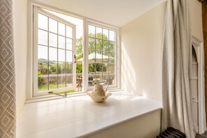 A room with a large window, a white bench, and a decorative bowl. - 3 Bed in Bridport (oc-89004) (Wootton Fitzpaine)
