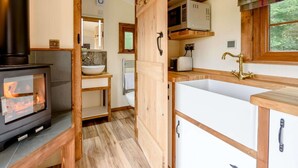 Cocina compacta con estufa de leña, lavamanos y ventana con vistas.