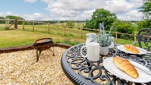 Un espacio al aire libre con mesa, parrilla y vistas al campo.