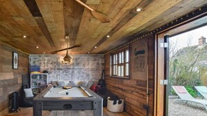 Ein Billardtisch in einem rustikalen Raum mit Holzwänden und einem Deckenventilator.
