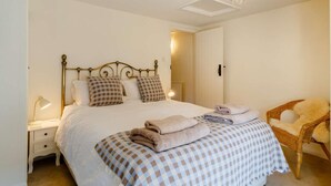 Una camera da letto con un letto, abat-jour, una coperta a quadri, una sedia e un lampadario.