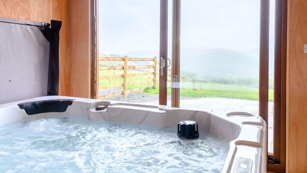 En træhytte med jacuzzi, store skydedøre og udsigt til en græsplæne.