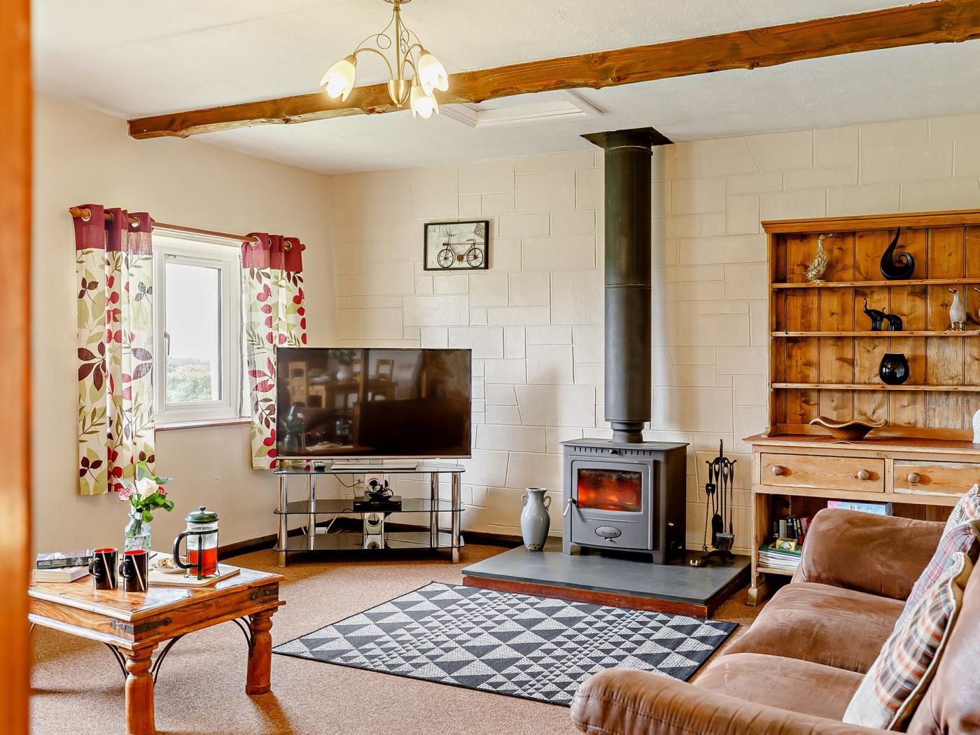 A living room with a television, a fireplace, a bookshelf, and a window with curtains.