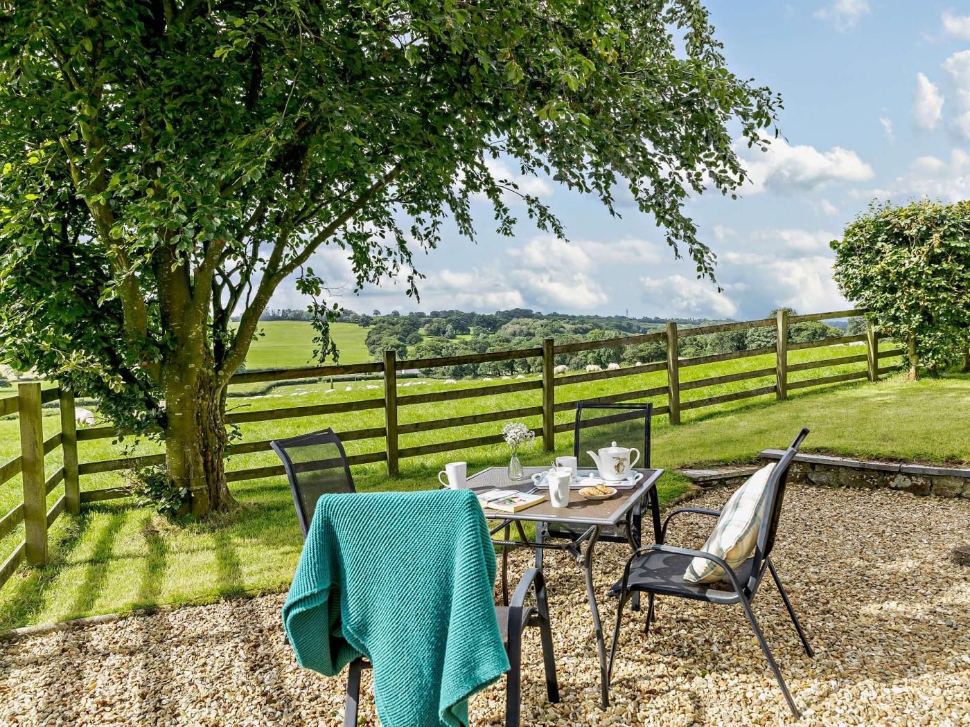 A table set outdoors with a view of a green field and a wooden fence.