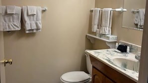 Un baño con inodoro, lavamanos y toallero.