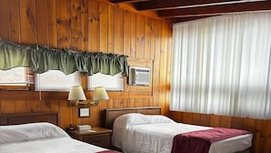 Una habitación con dos camas, paredes de madera, una ventana con persianas y aire acondicionado instalado en la pared.