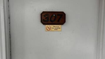 Une porte avec une plaque portant le numéro « 307 » et un panneau indiquant qu’il est interdit de fumer.