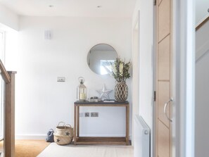Une pièce comprenant une console en bois, un miroir, un vase avec des fleurs, une lanterne et une décoration en forme d’étoile.