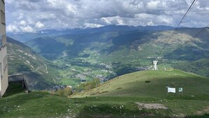 Eine gebirgige Landschaft mit einem Dorf, einem Turm und einem Gebäude mit Balkon.