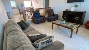 Ein Wohnzimmer mit einer Couch, einem Couchtisch, einem Fernseher und einem Deckenventilator.