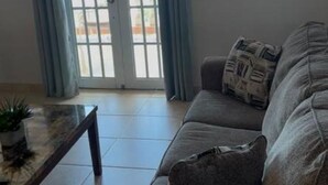 Ein Wohnzimmer mit einer Couch, einem Couchtisch und einem Fenster mit Vorhängen.