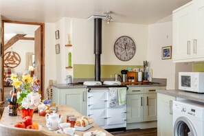 A kitchen with a central island, a washing machine, and a microwave. - 2 Bed in Okehampton (oc-89119) (Throwleigh)