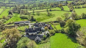 A rural landscape with rolling hills and a large house surrounded by green fields. - 2 Bed in Okehampton (oc-89119) (Throwleigh)
