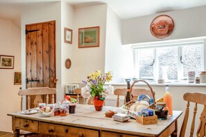 A kitchen with a wooden table set for breakfast, a window with a view, and a door with a rustic design. - 2 Bed in Okehampton (oc-89119) (Throwleigh)