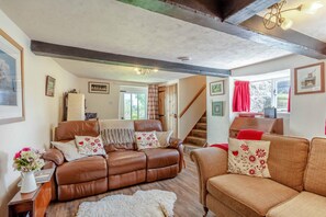 A cozy living room with a brown leather sofa, a patterned armchair, and a wooden coffee table. - 2 Bed in Okehampton (oc-89119) (Throwleigh)