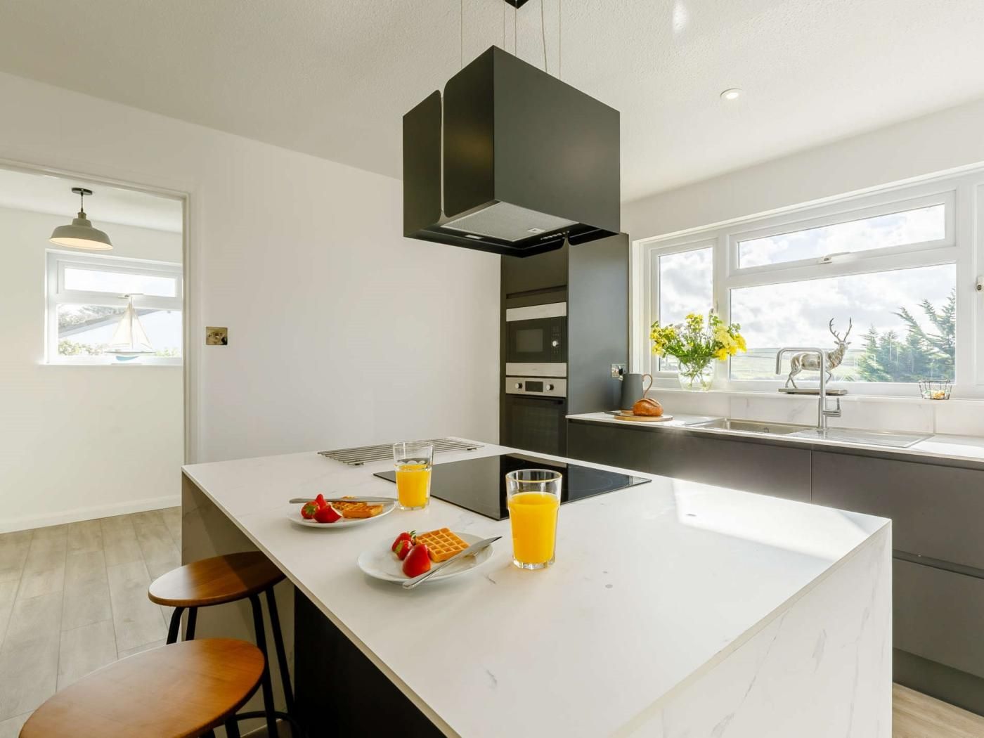 A modern kitchen with a central island, a built-in oven, and a window with a view.